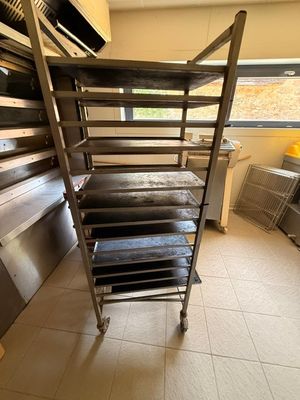 une cuisine équipée d'une cuisinière, d'un four et d'une étagère sur laquelle sont posées des plaques de cuisson