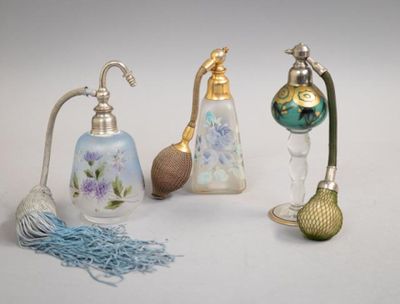 trois types différents de flacons de parfum posés sur une surface blanche