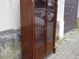 une armoire en bois avec des portes vitrées, située sur le côté d'un immeuble