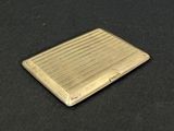 an image of a gold cigarette case sitting on a black surface