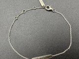 a silver bracelet with a bar on a chain
