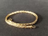 a close up of a gold bracelet on a black surface