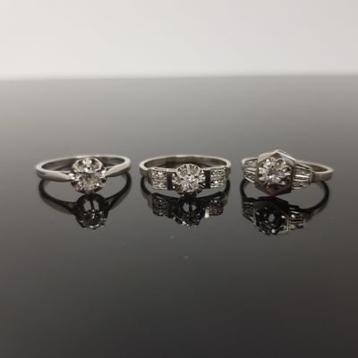 trois bagues de fiançailles ornées de diamants posées sur une surface noire