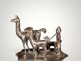 silver figurine of a man and a dog with a man on a bench