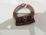 a brown brooch with purple stones on it