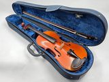 un violon orange repose dans un étui bleu posé sur une surface blanche