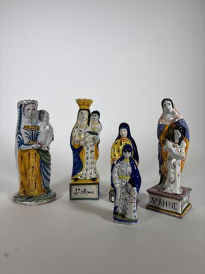 cinq figurines de tailles et de couleurs différentes posées sur une surface blanche