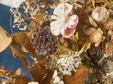 dried flowers in a vase on a table with a blue background