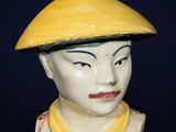 a ceramic figurine of a boy wearing a yellow hat