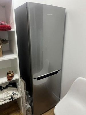 un réfrigérateur argenté et une chaise blanche dans une pièce