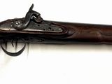 un vieux fusil exposé sur une surface blanche