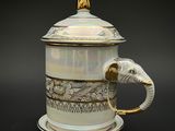 une tasse à café blanche et dorée ornée d'une tête d'éléphant