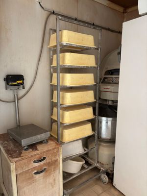 a rack with several trays of cheese on it in a kitchen