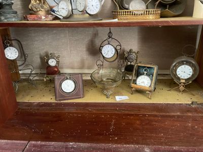 une étagère sur laquelle sont disposées de nombreuses horloges et photos différentes