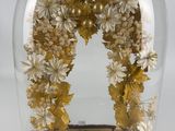 a glass cloche with gold and white flowers under a glass dome