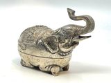 un éléphant argenté assis sur une surface blanche