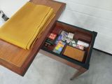a wooden table with a drawer with a yellow napkin and other items in it