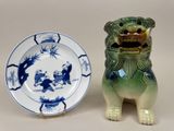 une assiette posée sur une autre assiette, à côté d'un chien en céramique