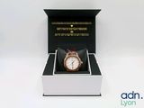 une boîte avec une montre à l'intérieur sur une surface blanche