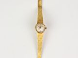 a close up of a gold wrist watch on a white surface