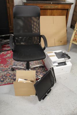 une chaise de bureau noire posée par terre à côté d'une pile de cartons