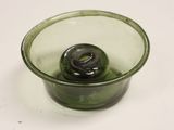 a green glass cup with a black lid on a white table
