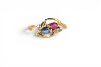 a close up of a gold ring with a pink and blue stone