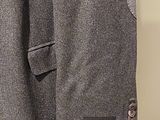a coat hanging on a wall with a tie on it