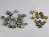 some coins are sitting on top of a table next to a pair of earrings