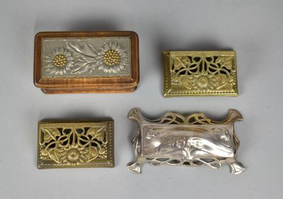 four pieces of silver and gold jewelry sitting on a white surface