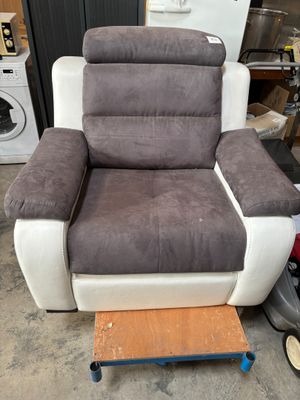 grey and white reclining chair in a garage with a washing machine in the background