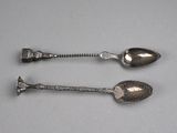pair of silver spoons on a gray surface with a silver handle