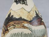 a small vase with a painting on it on a table