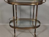 a brass and glass bar cart with two shelves on wheels