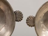 two silver bowls sitting next to each other on a table