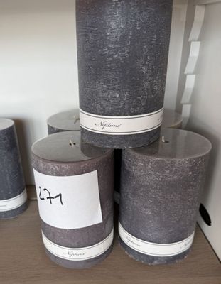 Des bougies sont empilées sur une étagère dans un magasin ; elles sont munies d'étiquettes.