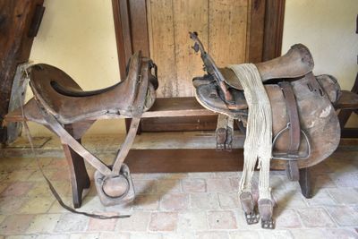 two saddles that are on a bench in a room