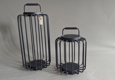 two black metal lanterns sitting next to each other on a white background