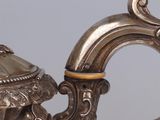 a silver tea pot with a handle on a table