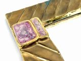 a close up of a gold and pink broochle