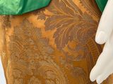 a close up of a mannequin wearing a green and gold dress