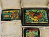 quatre petits tableaux dans un coffret posé sur une surface blanche