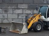une photo d'un petit engin de chantier garé devant un mur