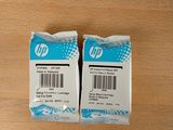 two packages of hp printer ink sitting on top of a wooden table
