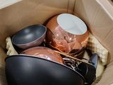 une boîte remplie de casseroles et de poêles posée par terre