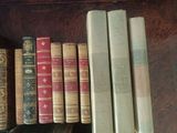 several old books are lined up on a shelf in a library