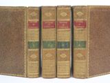 three old books sitting on top of each other on a white surface