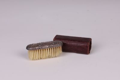 un petit pinceau et une petite boîte posés sur une surface blanche
