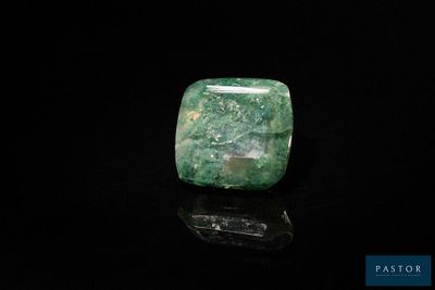 a close up of a green stone on a black surface