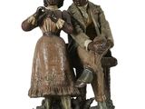 statue représentant un homme et une femme assis sur un banc avec un chien